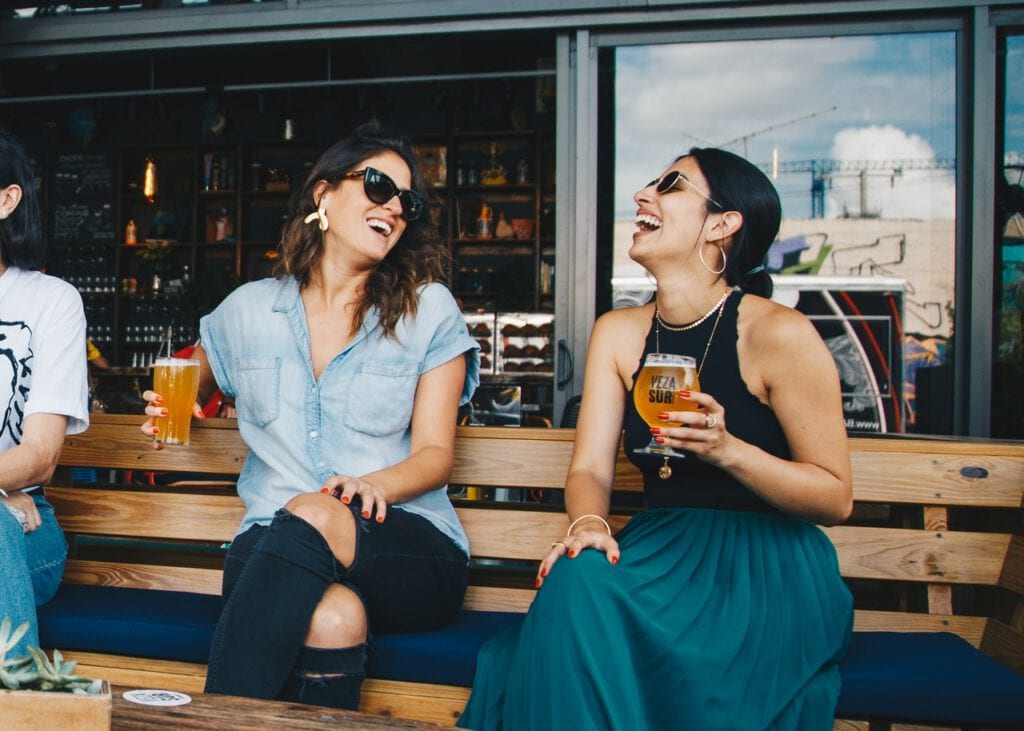 photo-of-two-women-drinking-beers-in-sun-on-bench-in-netherlands