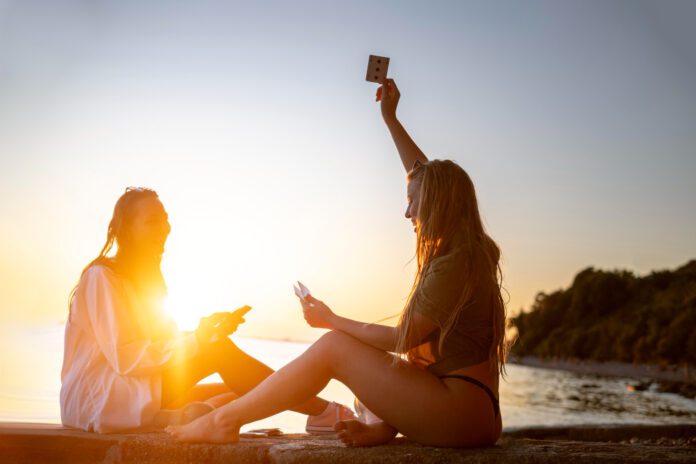 two-girls-sitting-by-the-sunset-having-fun