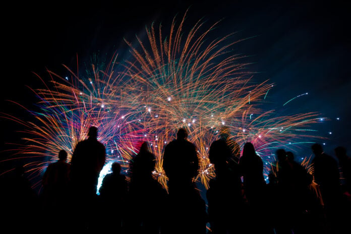 Silhouette-of-a-group-of-watching-bright-fireworks-against-a-dark-sky