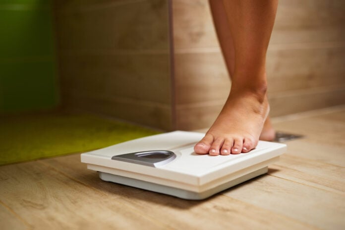 Woman weighing herself on weight scale in bathroom