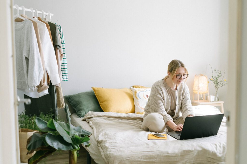 Person-sitting-on-their-bed-working-on-a-laptop-in-the-moring