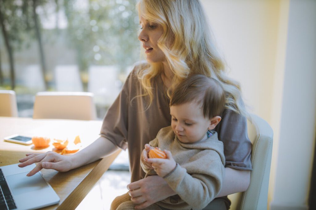 photo-of-woman-holding-child-on-lap-while-working-remotely-in-the-Netherlands