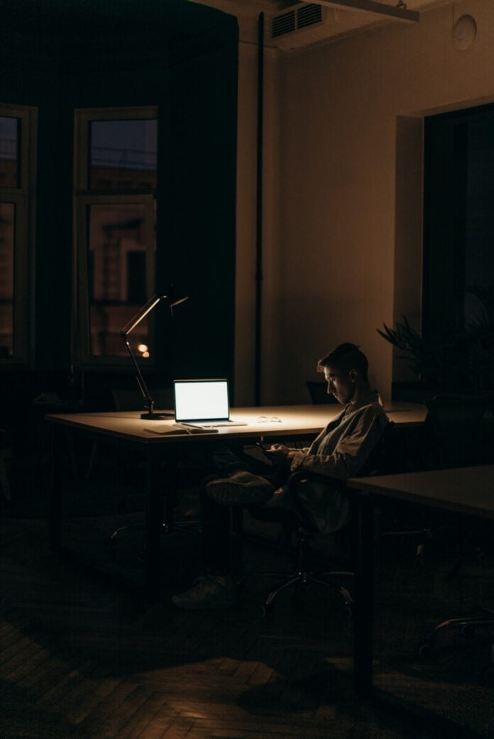 man sitting in dark at computer