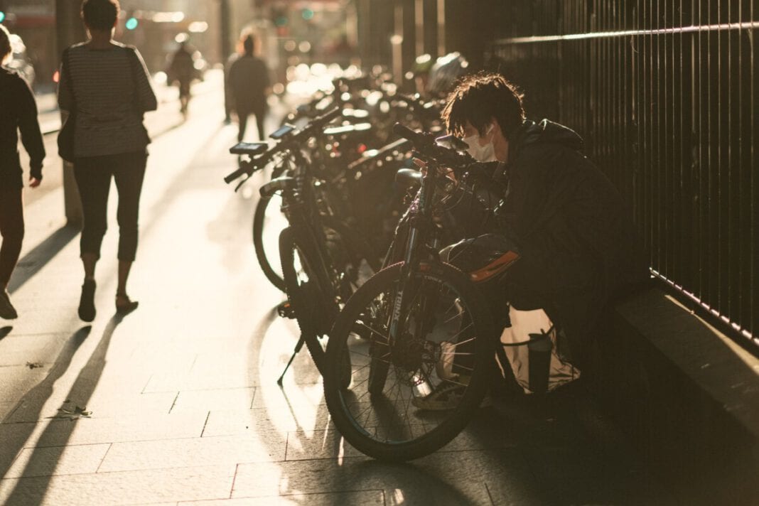 photo-of-a-man-wearing-a-face-mask-sitting-in-front-of-bikes