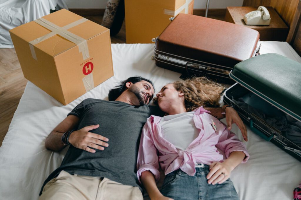 photo-of-girl-and-boy-laying-on-bed-with-suitcases-after-moving-to-holland