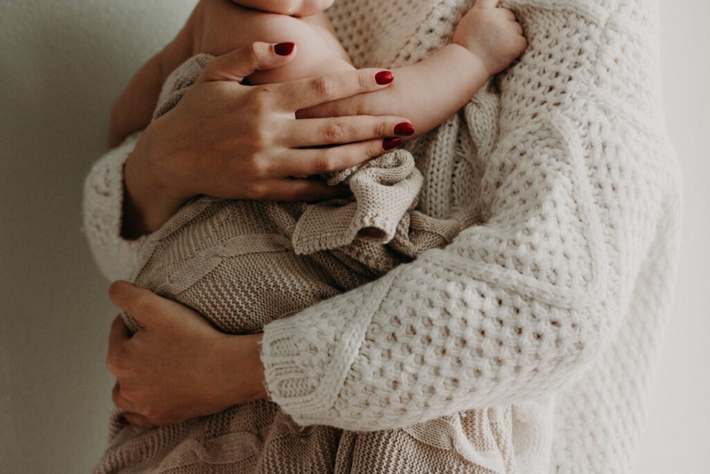 Woman-holding-her-newborn-baby-in-her-arms-with-red-fingernails-maternity-leave