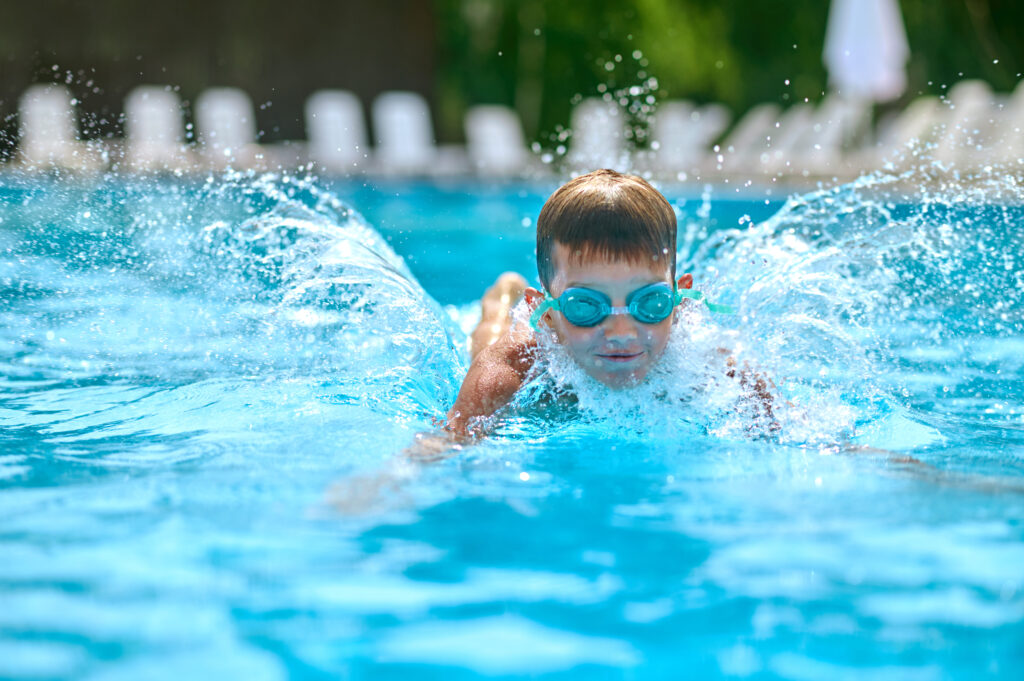 photograph-of-a-boy-wearing-goggles-swimming-in-an-outdoor-pool
