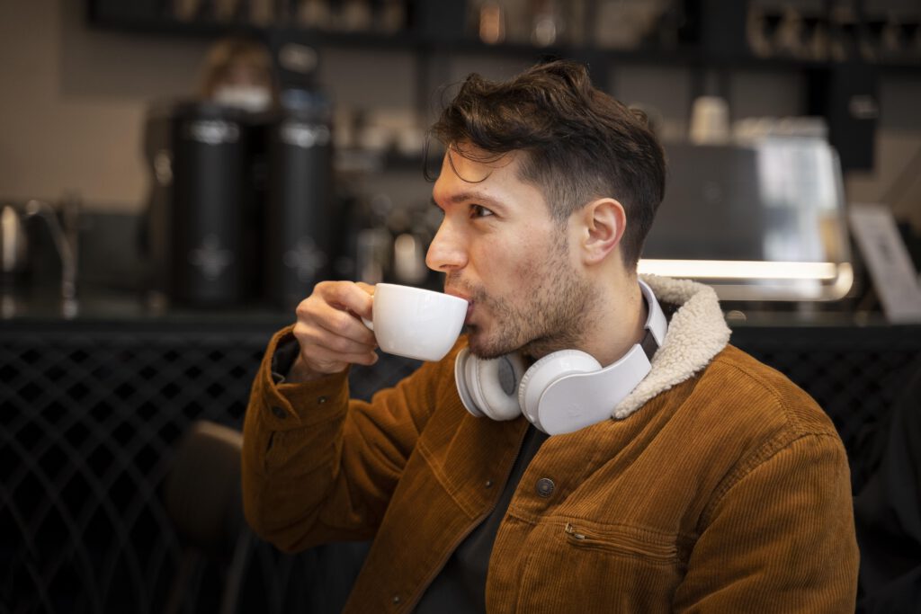 카페에서 커피를 마시며 코듀로이 재킷을 입은 남자의 사진
