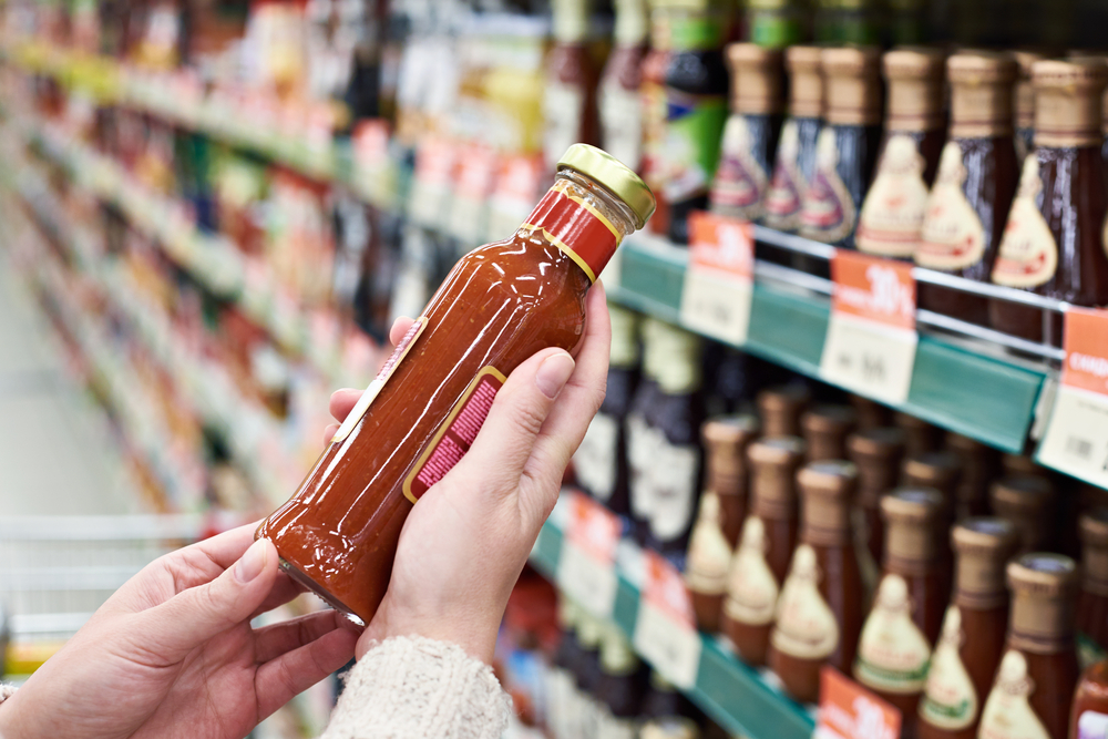 photograph-of-a-shopper-holding-a-bottle-of-hot-sauce-in-a-supermarket