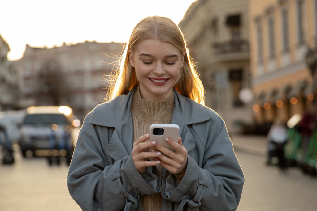 photograph-of-a-dutch-woman-holding-her-phone-and-smiling-whilst-she-strolls-down-a-street-and-makes-bank-transfer