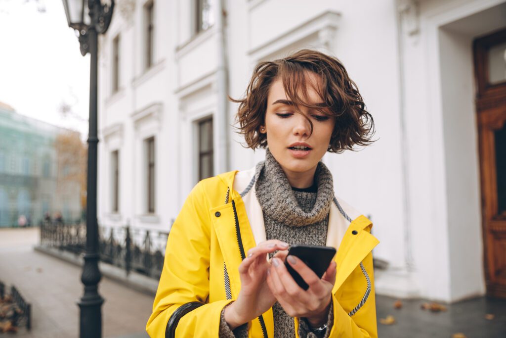 photograph-of-a-woman-in-a-yellow-raincoat-typing-on-her-phone-with-a-dutch-sim-only-plan