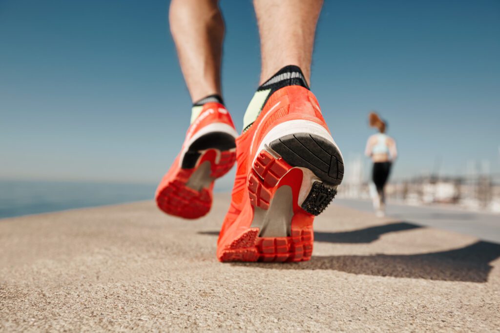 photograph-of-man-jogging-in-orange-shoes-along-a-sandy-path