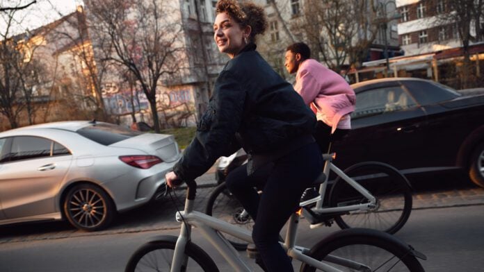 photograph-of-two-people-riding-vanmoof-e-bikes-down-a-city-street