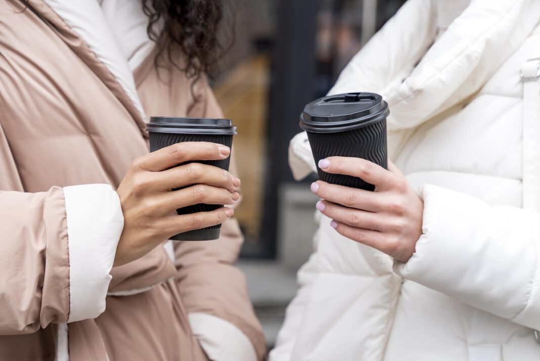 photograph-of-two-women-holding-plastic-coffee-cups