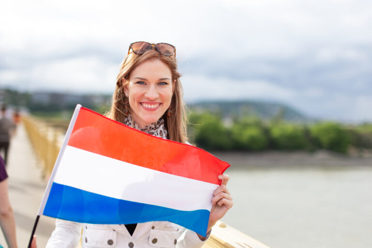 picture-of-dutch-woman-holding-dutch-flag-posing-for-camera-with-view-of-lake-in-back-the-netherlands