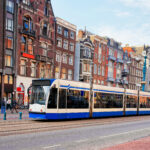 travessia de bonde público-damrak-rua-principal-lotada-de-turistas-amsterdã-países baixos