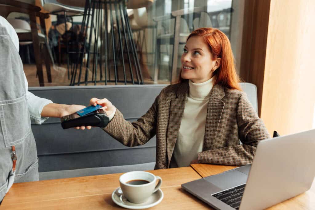 redheaded-woman-sitting-at-a-cafe-in-the-netherlands-and-using-her-dutch-bank-card-to-pay-for-some-coffee