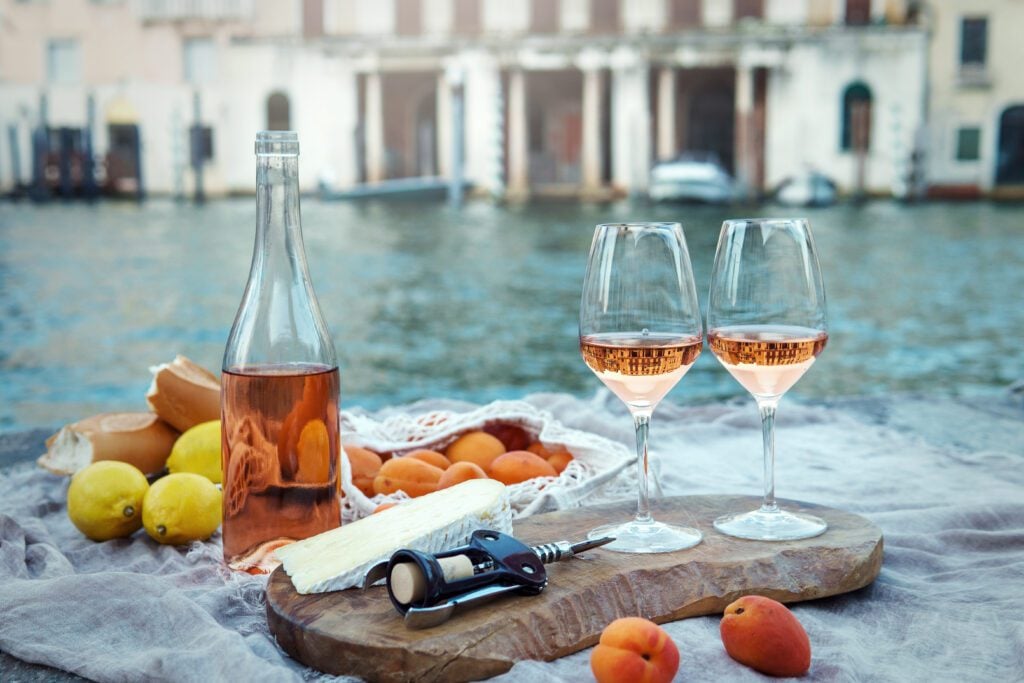 Rose-wine-fruits-and snacks-on-the-wooden-pier-during-picturesque-picnic-on-the-wooden-gondola-dock