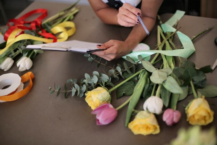 florist-looking-at-orders-with-floers-on-table