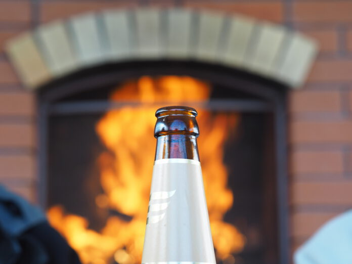 glass-beer-bottle-in-front-of-brick-house-on-fire