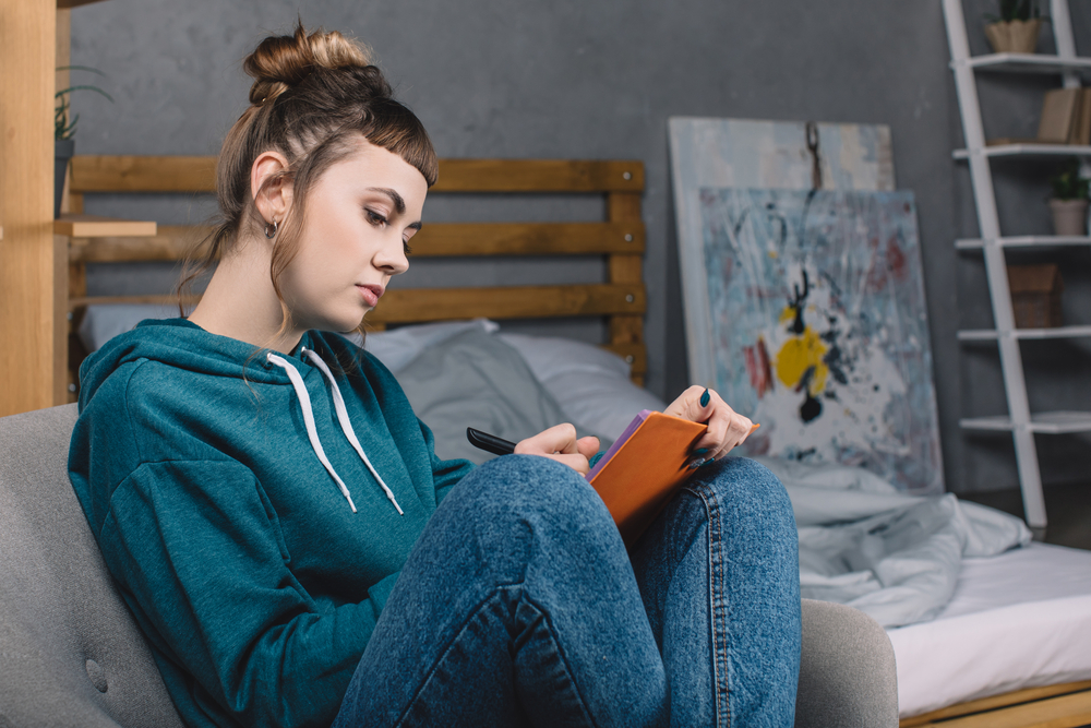 girl-writing-in-a-notebook-figuring-out-what-Dutch-health-insurance-she-needs