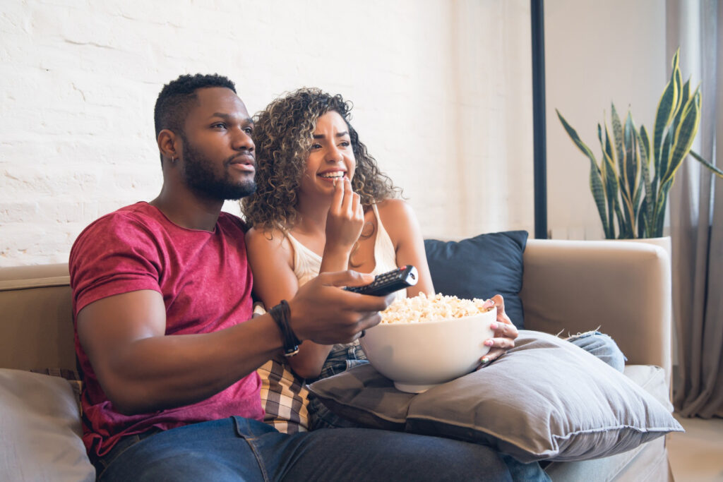 photo-of-couple-sitting-on-couch-watching-tv-afer-setting-up-utilities-when-moving-house-in-the-Netherlands