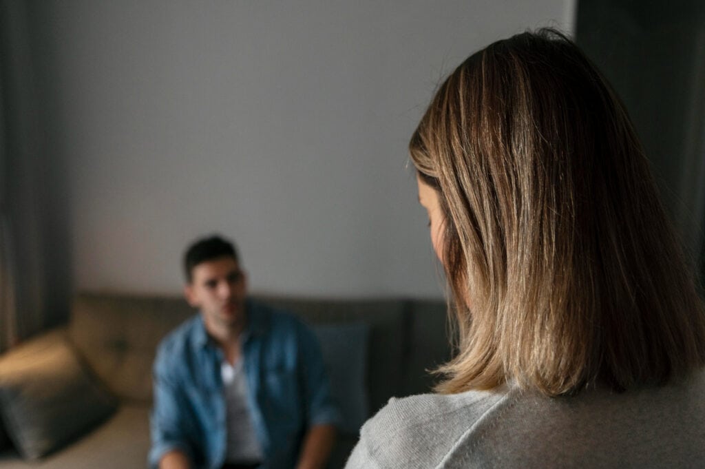 photo-of-back-of-woman's-head-with-man-sitting-on-couch-in-background-discussing-getting-a-mediator-while-separating-in-the-netherlands