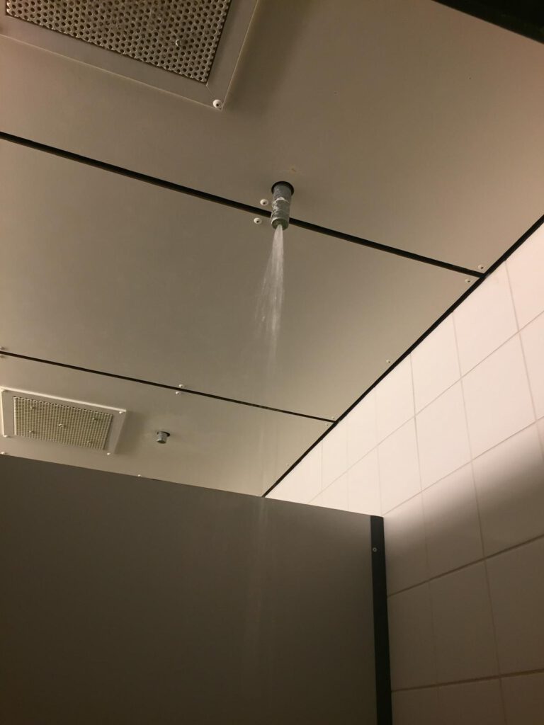 photo-of-the-prison-shower-with-water-spurting-out-of-a-small-pipe-in-the-ceiling