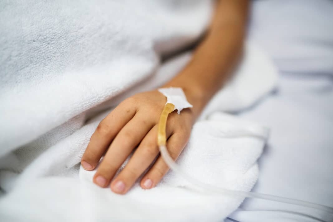 photo-of-hand-of-sick-child-with-IV-resting-on-bed