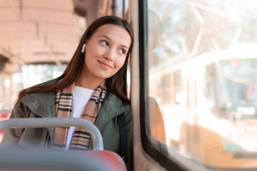 smiling-young-woman-passenger-leaning-against-tram-window-looking-outside