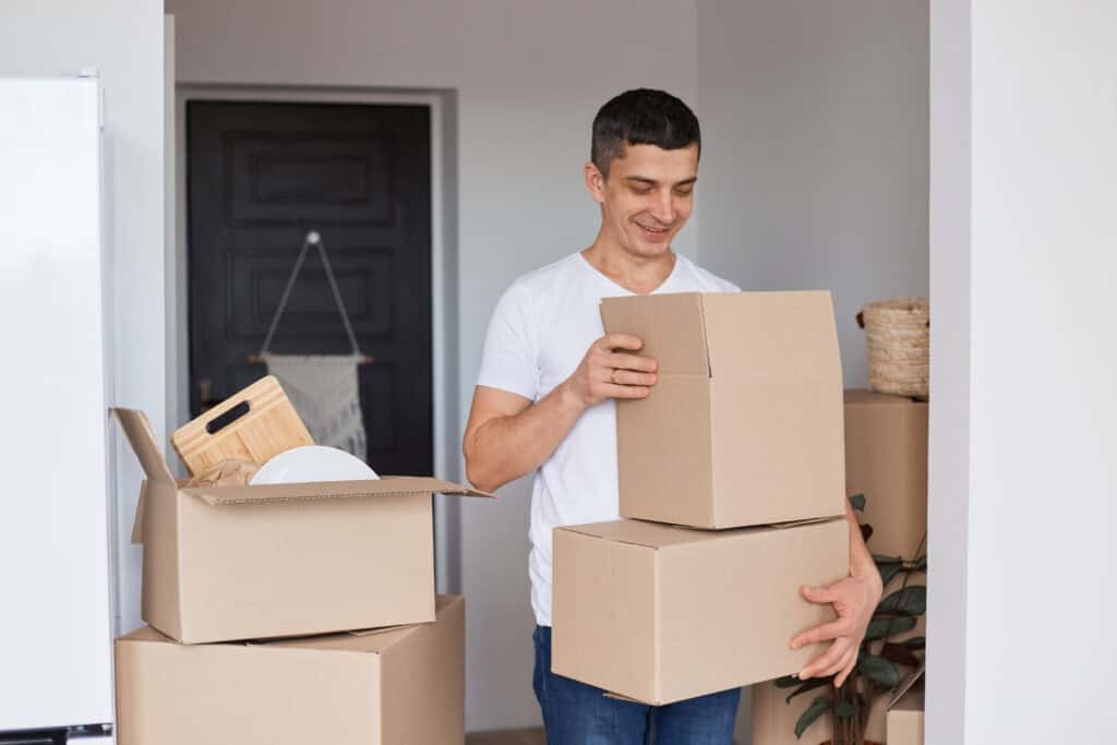 smiling-young-man-posing-new-flat-with-cardboard-boxes-moving-house-after-getting-mortgage-with-ING-bank