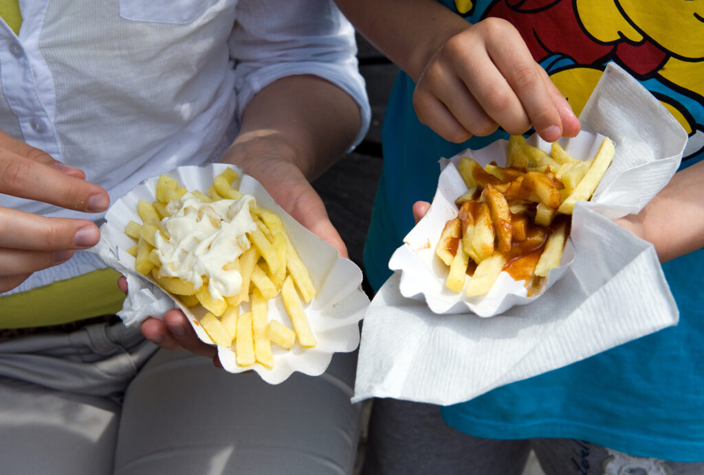 People eating Dutch french fries with mayonnaise and peanut sauce