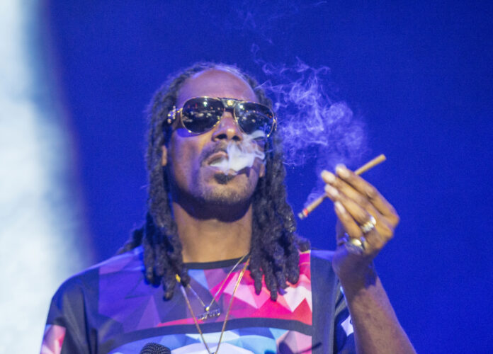 photo-of-snoop-dogg-on-stage-in-las-vegas-smoking-a-joint-or-cigarette-with-blue-background