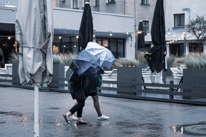 Two-people-hiding-behind-umbrella-from-rain-and-strong-wind