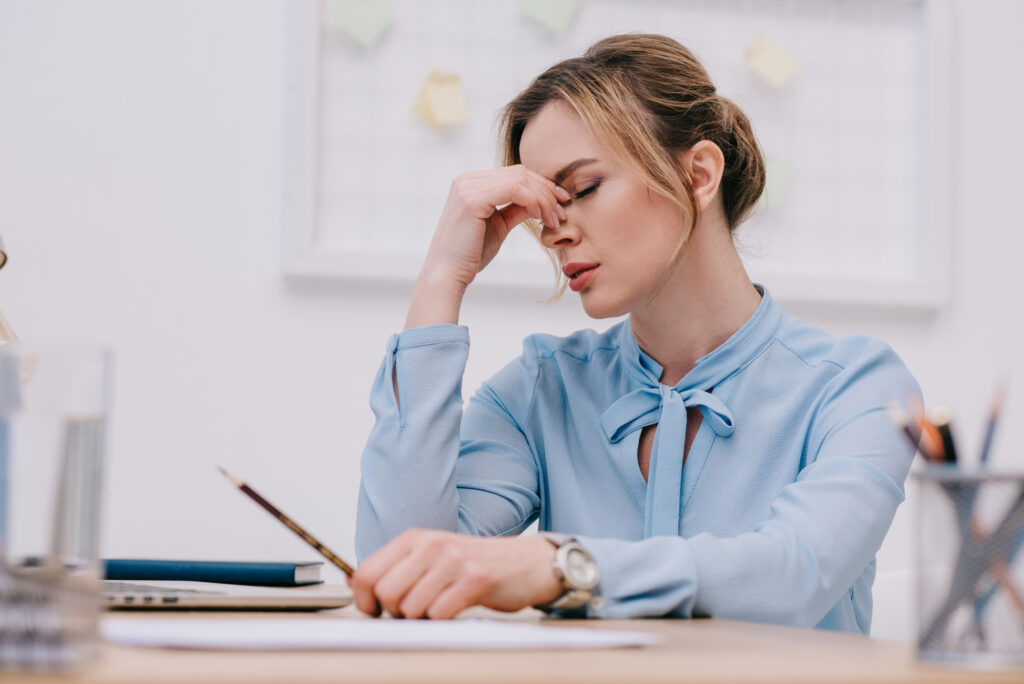 photo-of-elegantly-dressed-woman-sitting-at-a-desk-holding-her-head