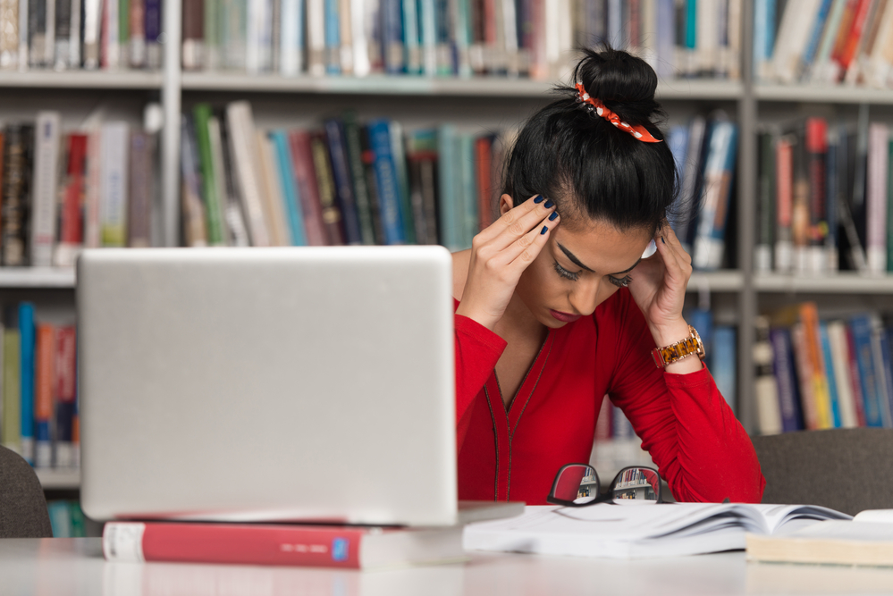 photo-of-stressed-student-in-dutch-university-library-sitting-with-laptop-and-textbooks
