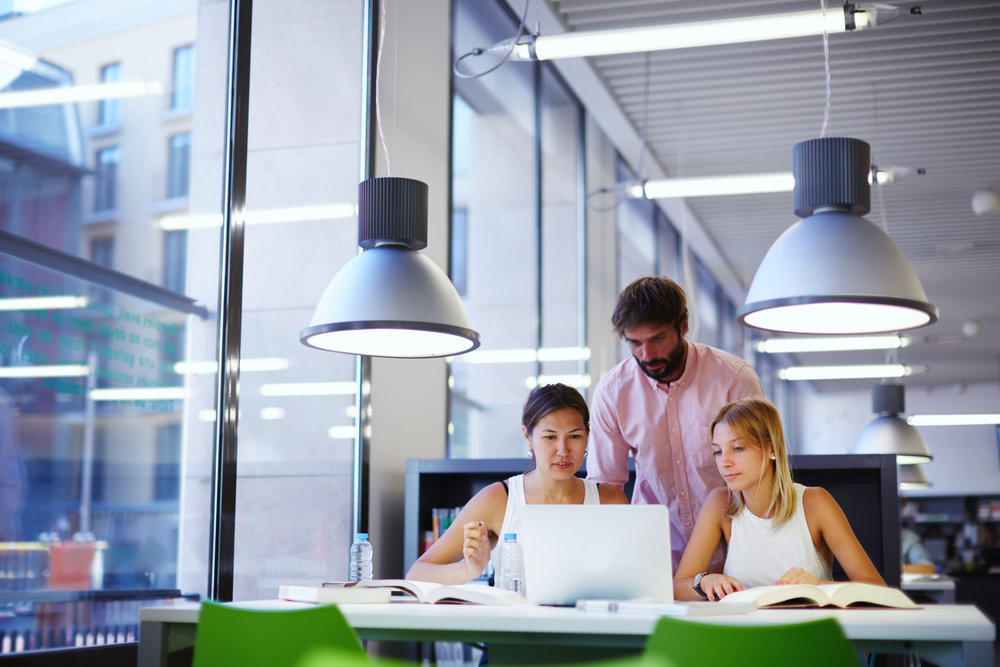 Three-students-standing-around-a-laptop-and-books-studying-Dutch