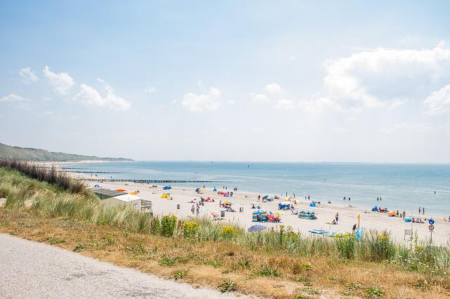 view-of-sunny-dutch-beach-from-side-of-the-road-with-people-sunbathing-in-distance 