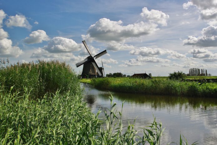 photo-of-windmill-by-lake-on-sunny-but-cloudy-day
