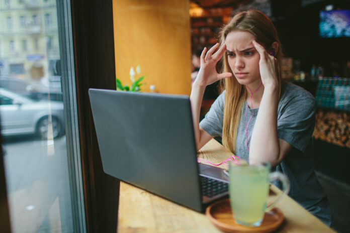 photo-of-woman-looking-stressed-while-looking-at-laptop-in-cafe