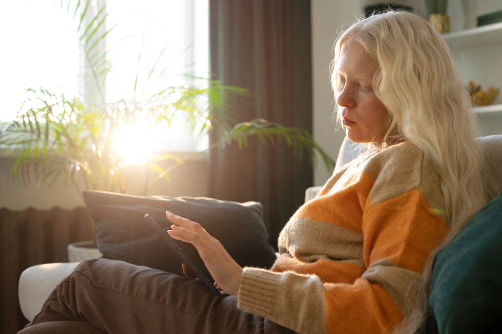 photo-of-woman-holding-phone-while-sitting-on-couch-in-the-netherlands-looking-up-how-to-switch-energy-providers
