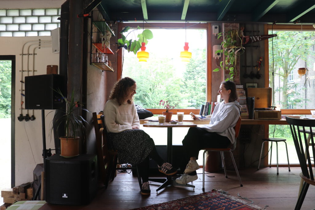 photo-of-two-girls-having-coffee-in-charming-cafe-bind-in-the-hemburg-terrain-in-zaandam