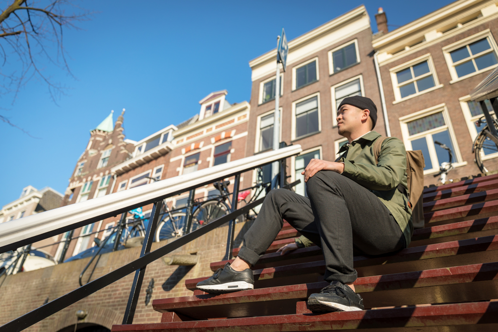young-man-sitting-on-steps-to-amsterdam-rental-apartment