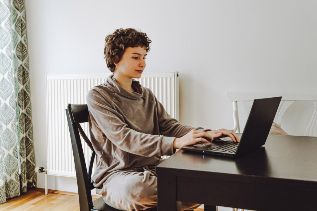 photo-of-woman-sitting-at-home-on-laptop-after-moving-house-in-the-Netherlands-and-completing-utilities-checklist