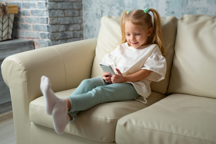 very-young-dutch-child-using-social-media-on-her-mobile-phone-as-she-relaxes-at-home