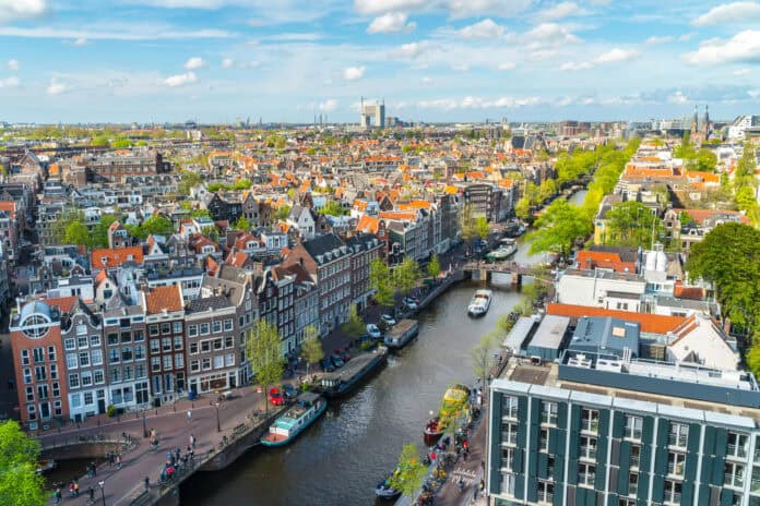 view-of-amsterdam-skyline-with-boat-passing-through-canal