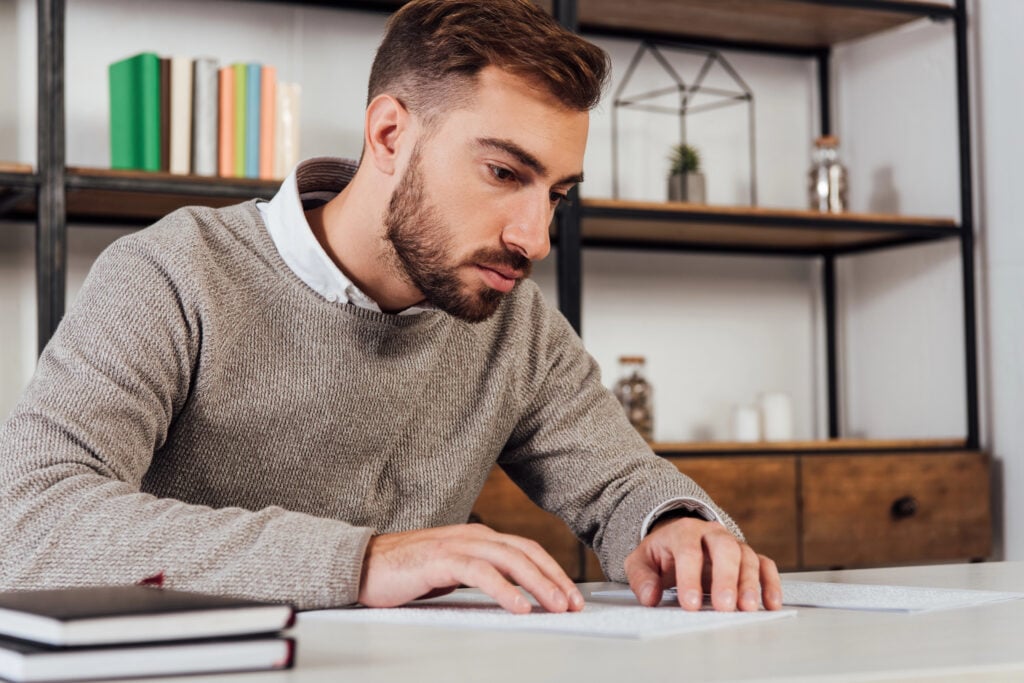 photo-of-visually-impaired-man-sitting-at-deask-and-reading-bank-statement-in-braille