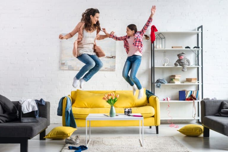 photo-of-mother-and-daughter-jumping-off-yellow-couch-in-bright-living-room-after-making-winning-bid-on-house-netherlands