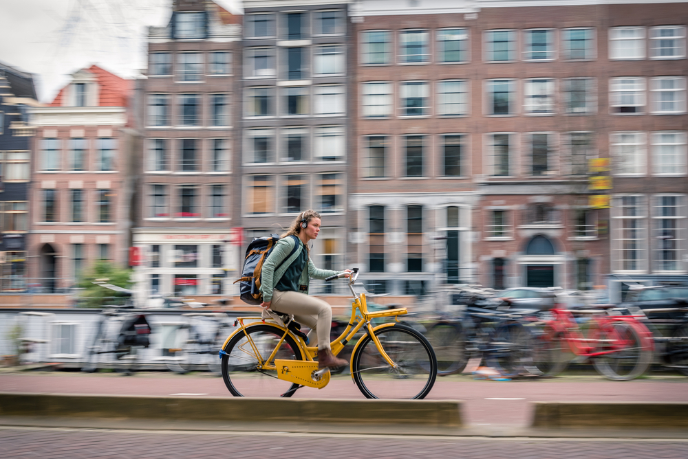 woman-biking-fast-in-amsterdam-netherlands-while-wearing-headphones