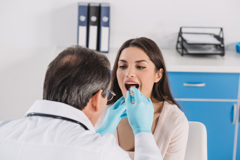woman-getting-throat-checked-by-doctor